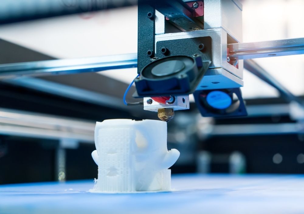 Commercial 3D printer printing a white plastic part in Manchester