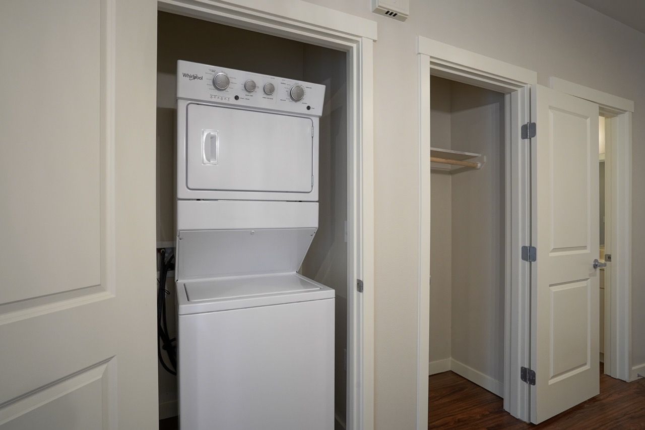 In-unit laundry closet with a white stacked washer and dryer between doors.