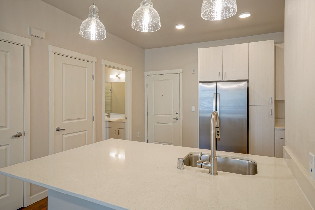 Kitchen with island, sink, and stainless steel fridge in a modern apartment.