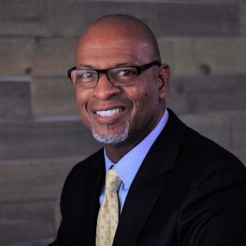A man in a suit and tie is smiling for the camera.