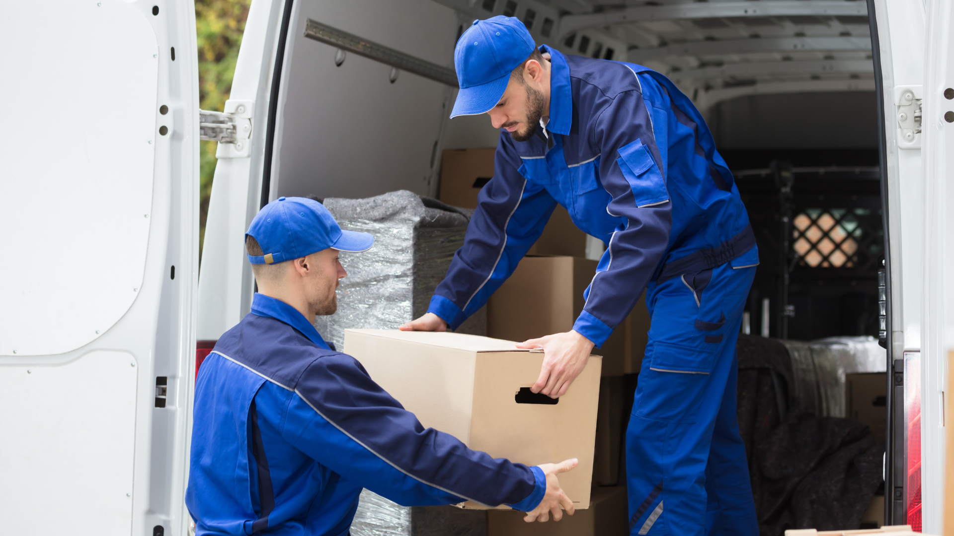 Two delivery men are loading boxes into a van.