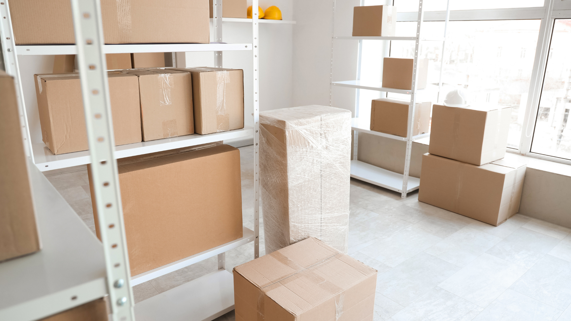 Empty warehouse with metal shelving and several cardboard boxes on the floor and shelves