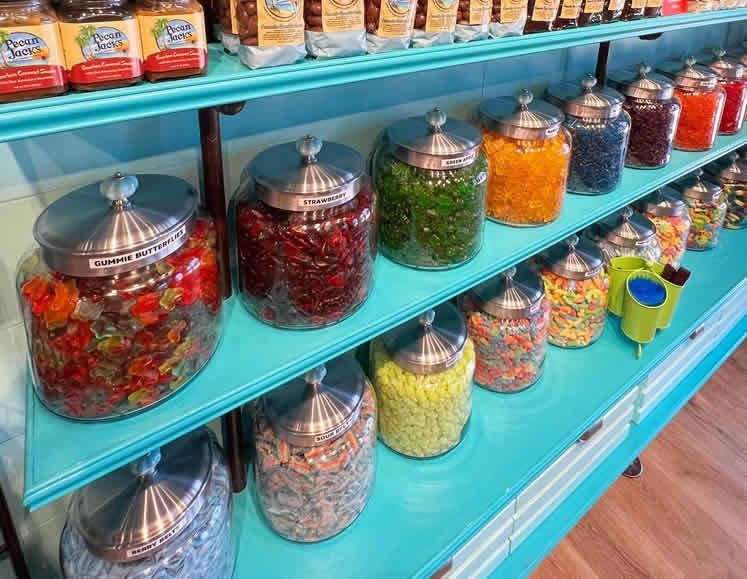 A store shelf filled with jars of candy.