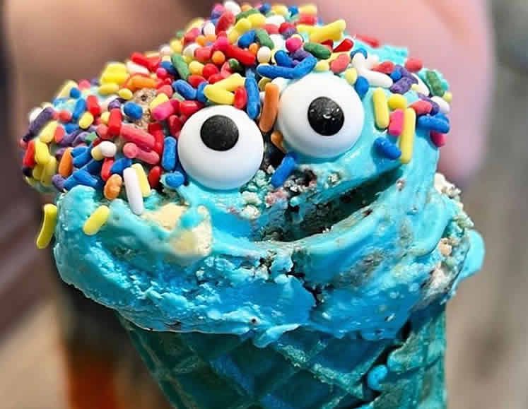 A cookie monster ice cream cone with blue frosting and sprinkles