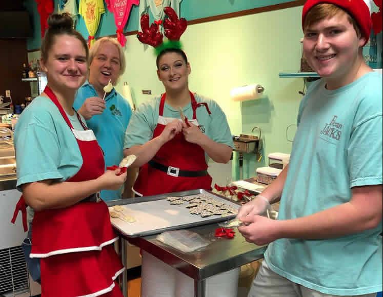 A group of people wearing aprons and santa hats are working in a kitchen