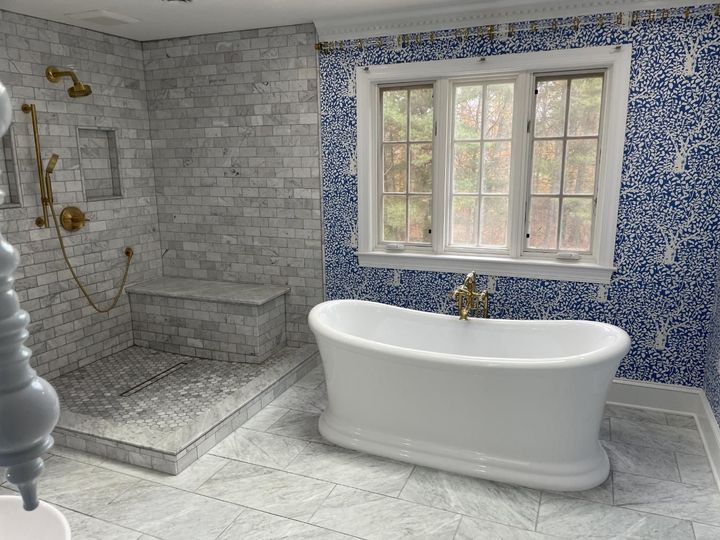 Bathroom with a white freestanding tub, blue mosaic accent wall, and marble tiled shower.