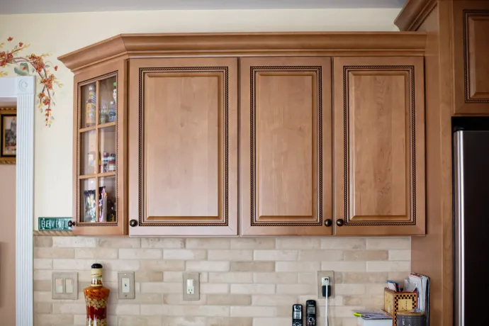 Wooden kitchen cabinets over a tiled backsplash. 