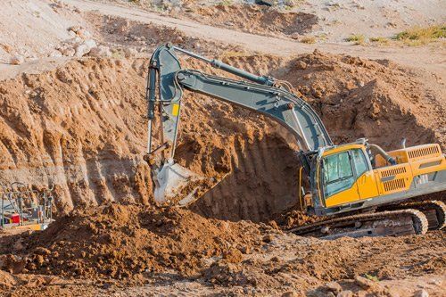 Un grande escavatore sta scavando una buca nel terreno.