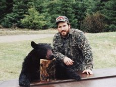 A man is standing next to a black bear on a table.