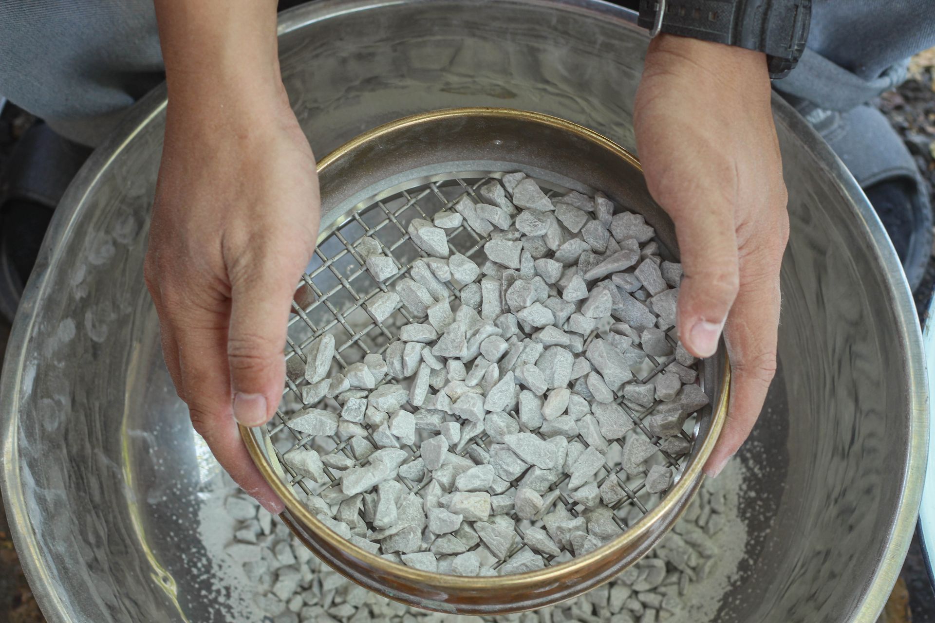 Engineers sifting aggregate for particle size reduction in a lab setting.