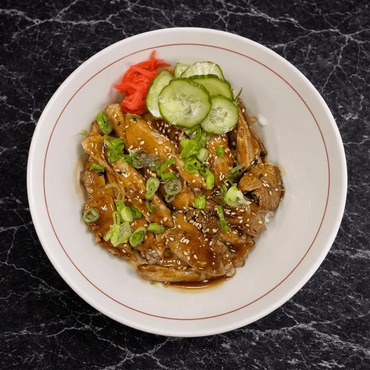 A bowl of teriyaki chicken over rice with steamed cabbage, topped with sesame seeds on a dark, textured background.