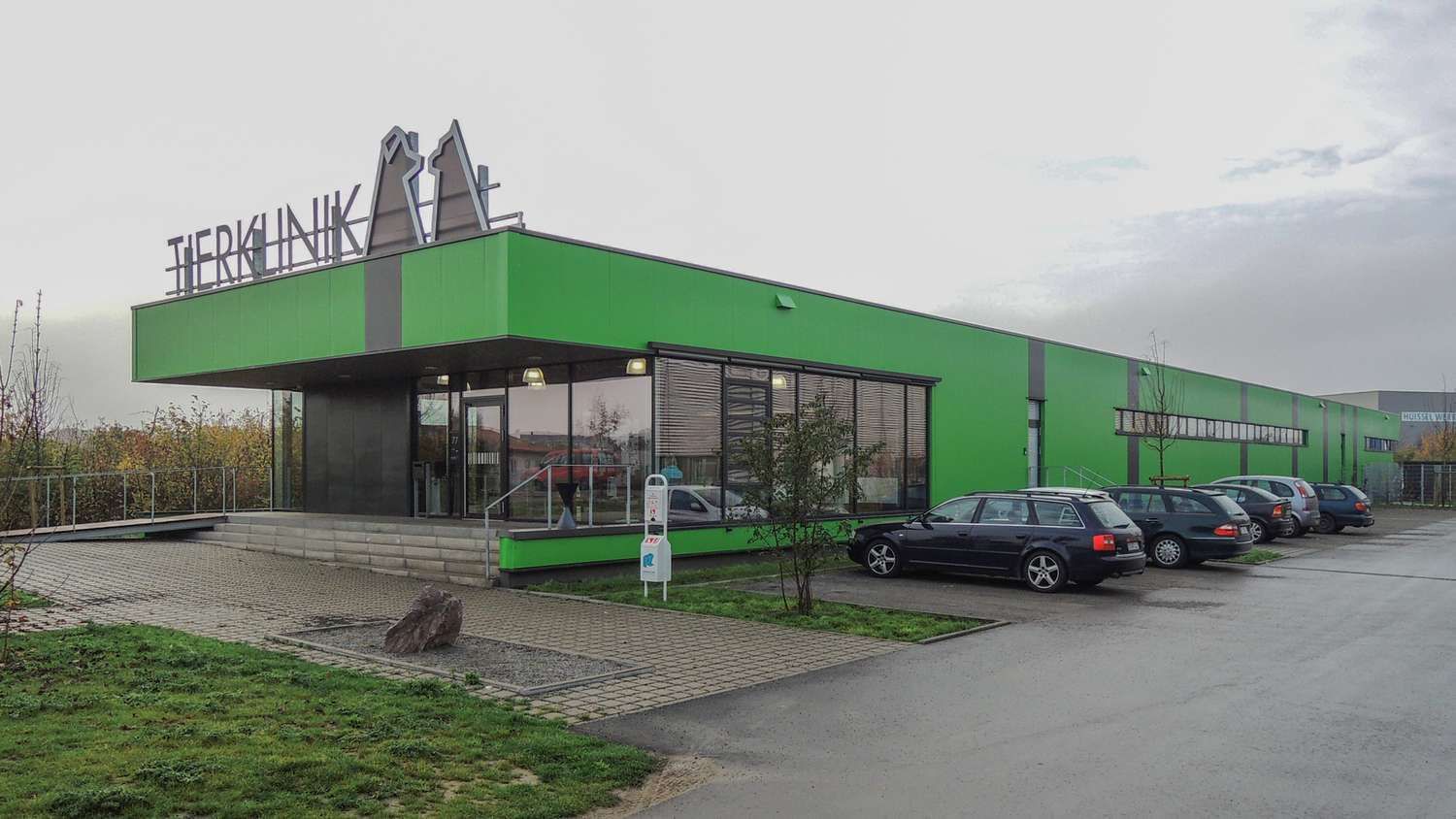 Ein grünes Gebäude mit davor geparkten Autos.