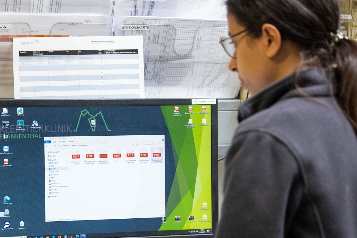 Eine Frau mit Brille schaut auf einen Computerbildschirm.