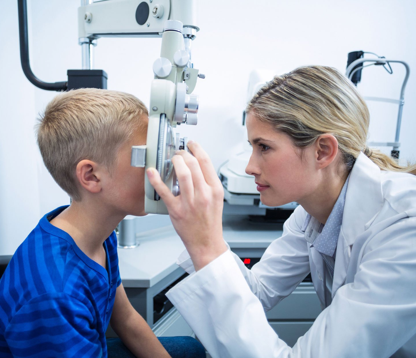 Optometrist performing an eye exam on a young boy