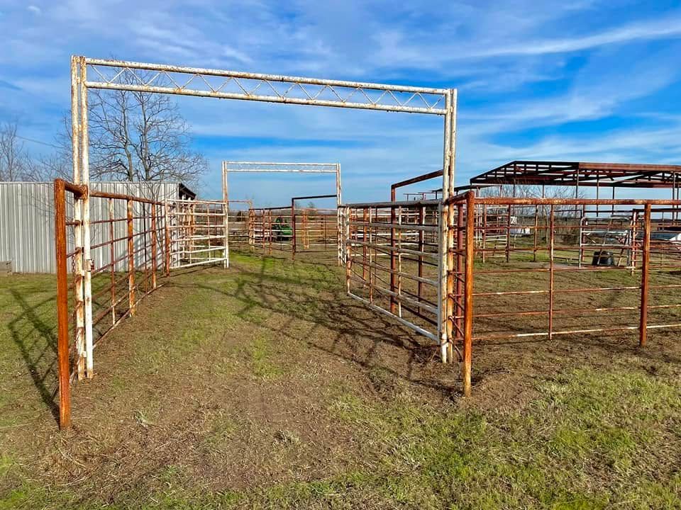 Rusty metal livestock pens in a grassy field under a blue sky