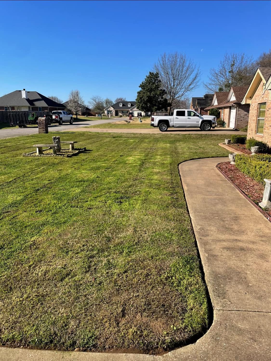 Suburban front yard with green lawn, concrete walkway, white truck, and clear blue sky
