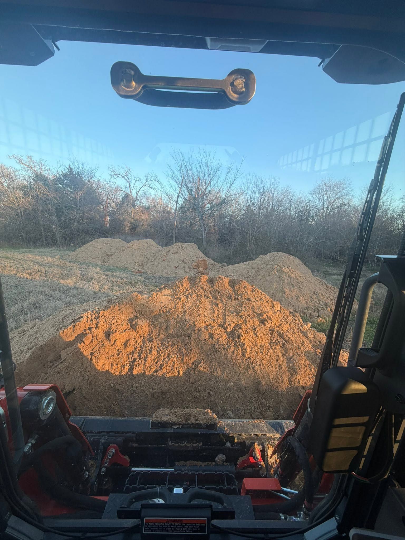 View from a construction cab at a gravel pile under a blue sky