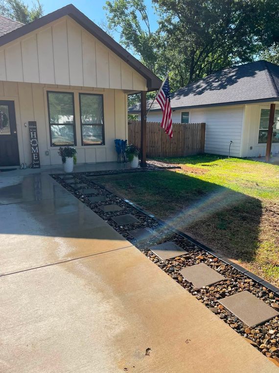 Suburban house front yard with driveway, walkway, trees, and an American flag near the garage.