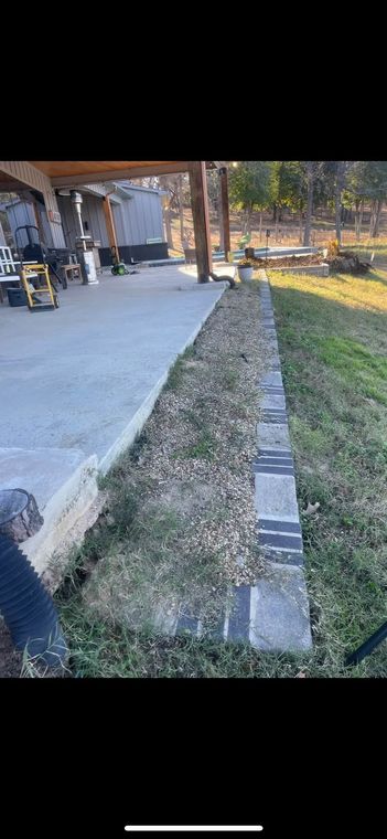 Outdoor walkway beside a building, with a concrete path, grassy edge, and people in the background.