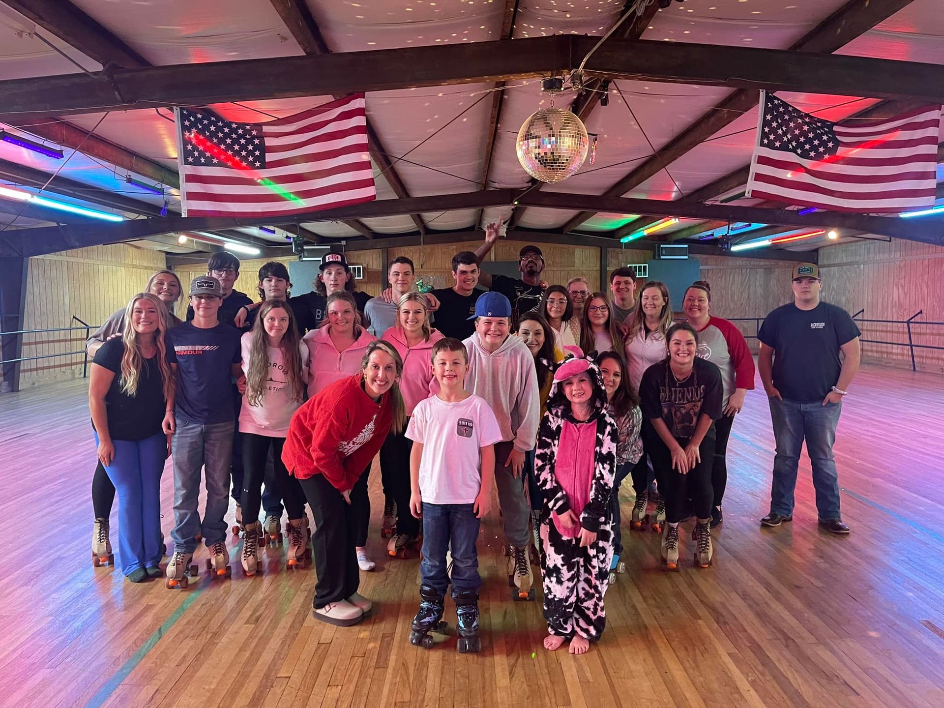A group of people are posing for a picture in a roller rink.