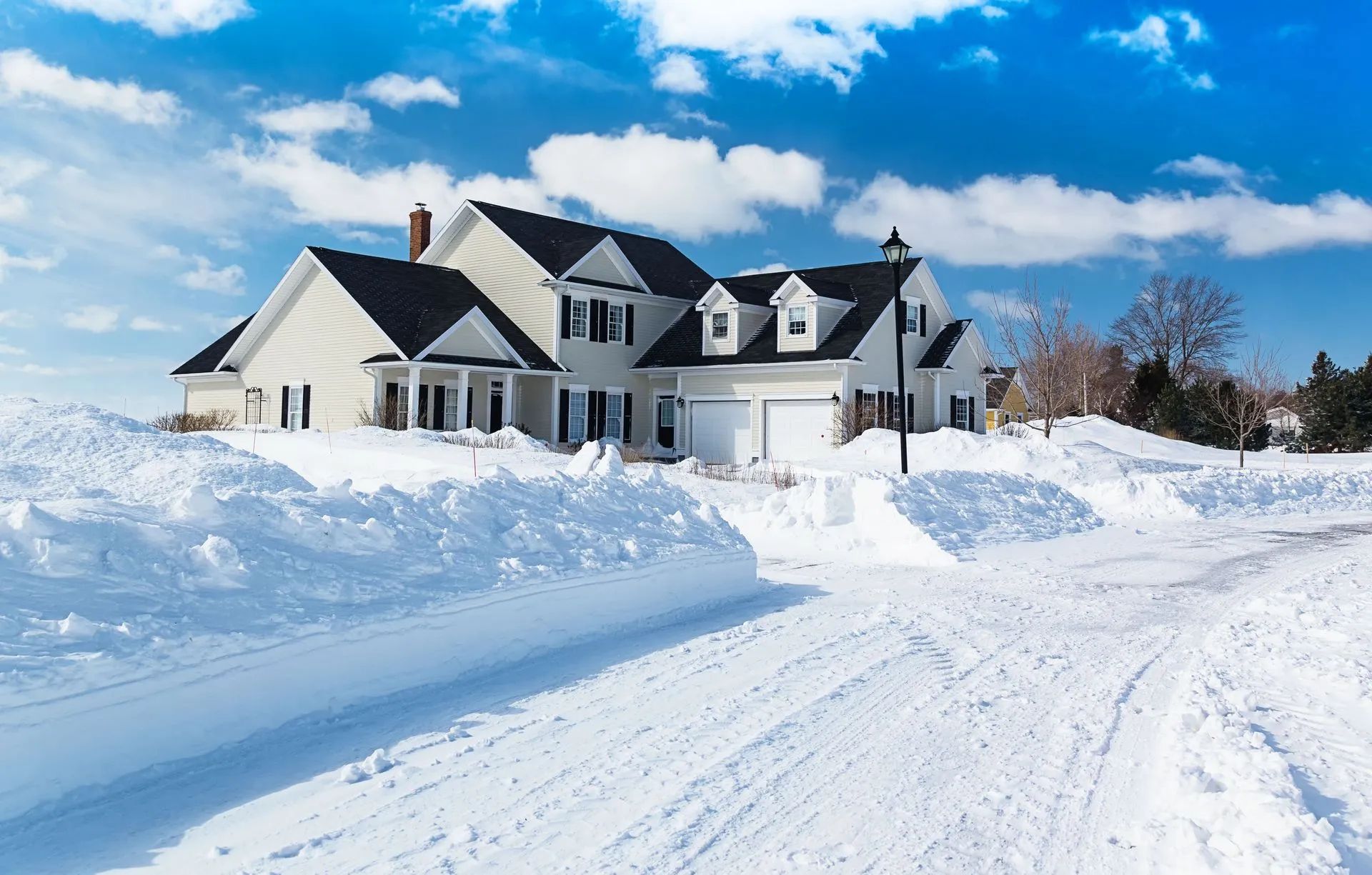 A large white house is surrounded by snow on a sunny day.