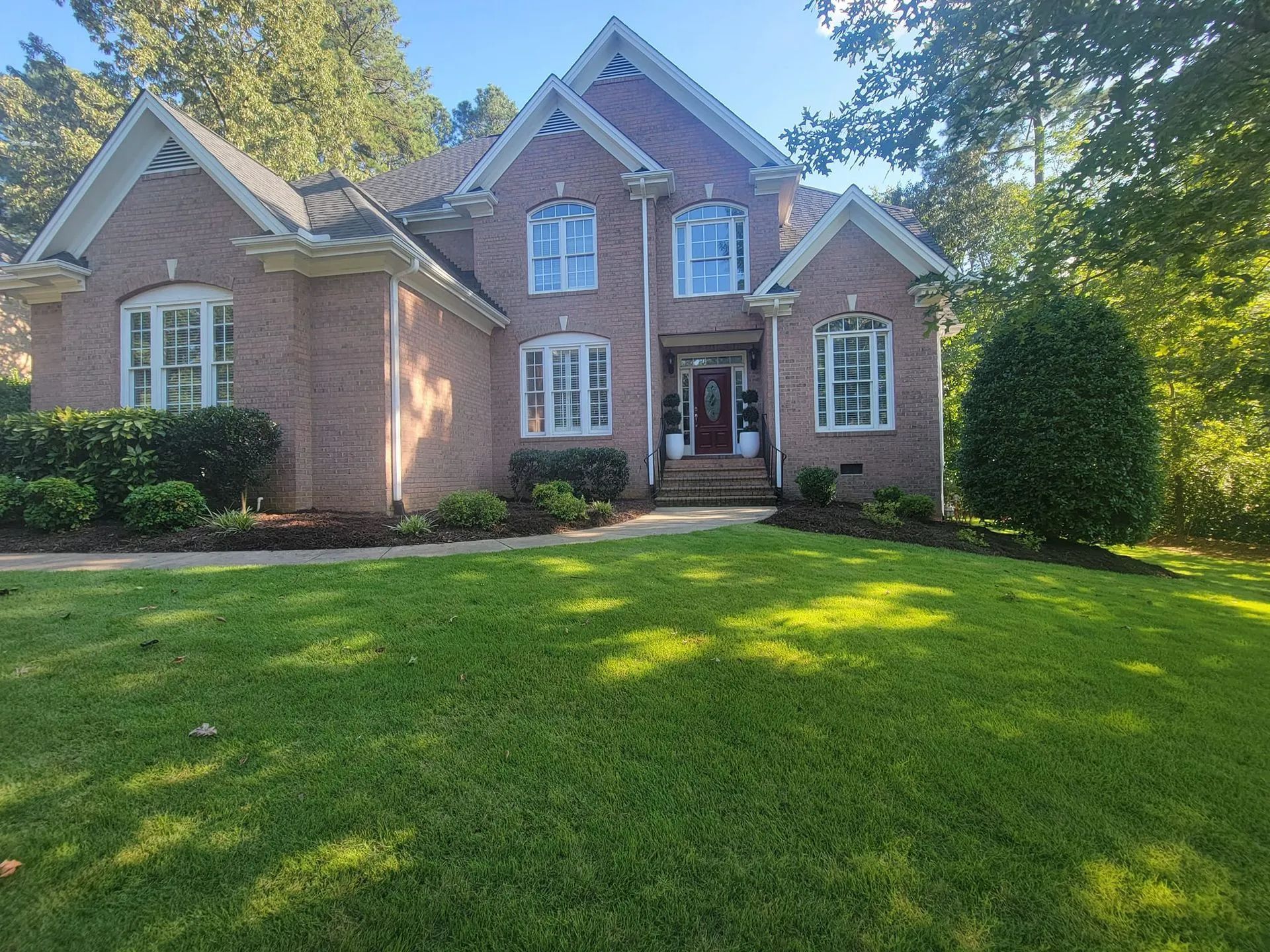 A large brick house with a lush green lawn in front of it.
