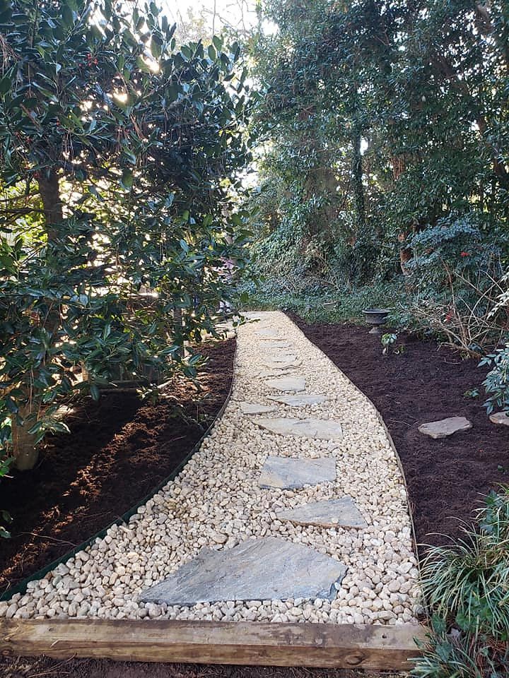 A stone walkway in the middle of a forest surrounded by trees.