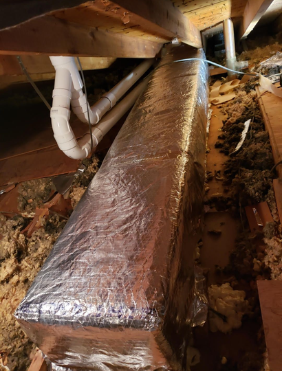 A furnace in a basement setting. The unit is silver and connected to ductwork.