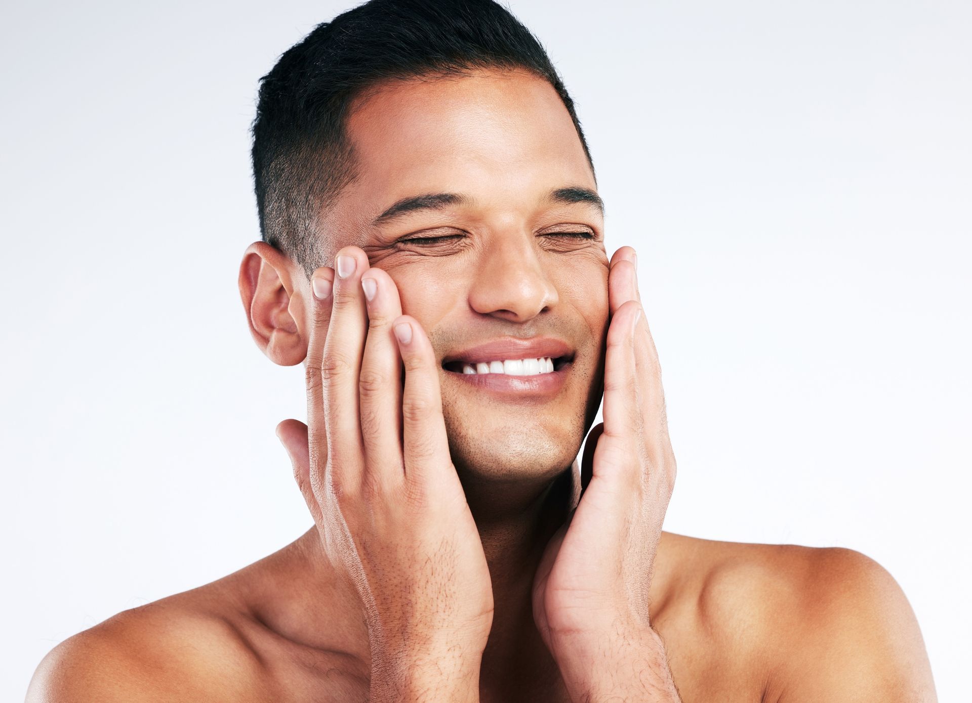 Smiling person applying moisturizer to their face against a white background