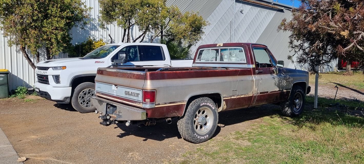 Two Trucks Parked Near a Building. One White, Modern Pickup Truck and An Older — Sparky's 4x4 In Taminda, NSW