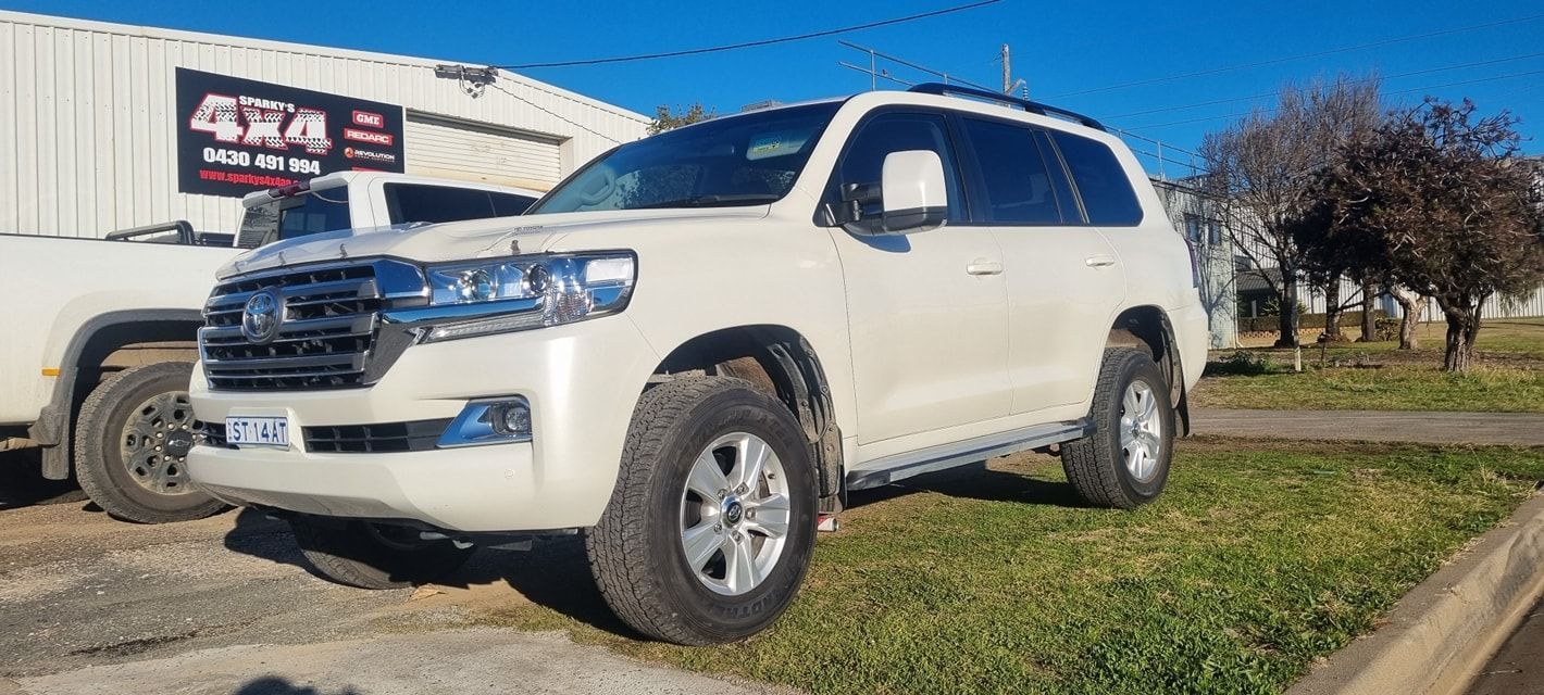 White Suv Parked on Grass Near a Building with 4x4 Sign — Sparky's 4x4 In Armidale, NSW