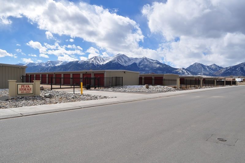 Low building along a road with snow-capped mountains under a partly cloudy sky