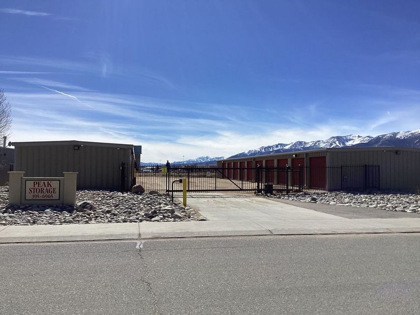 Modern single-story buildings with a paved entrance, rock landscaping, and mountains under a blue sky.