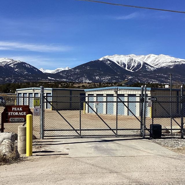 Gated storage yard with snow-capped mountains in the background under a clear blue sky