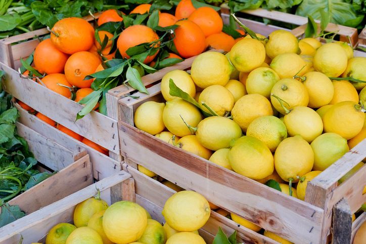 Casse di arance e limoni impilate in un mercato o in una bancarella di prodotti agricoli.