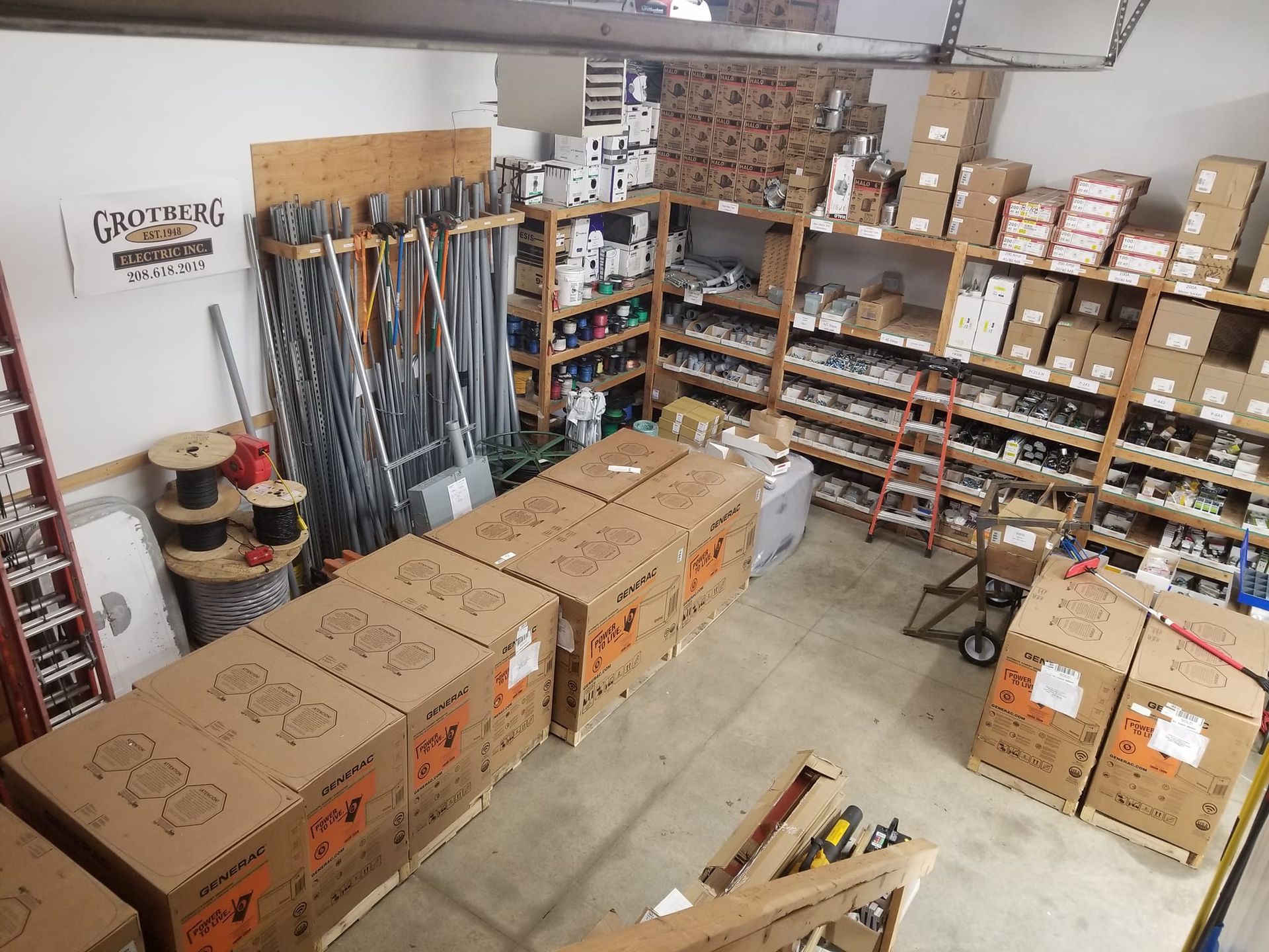 Warehouse interior with stacked boxes, shelves of supplies, and bundled metal rods
