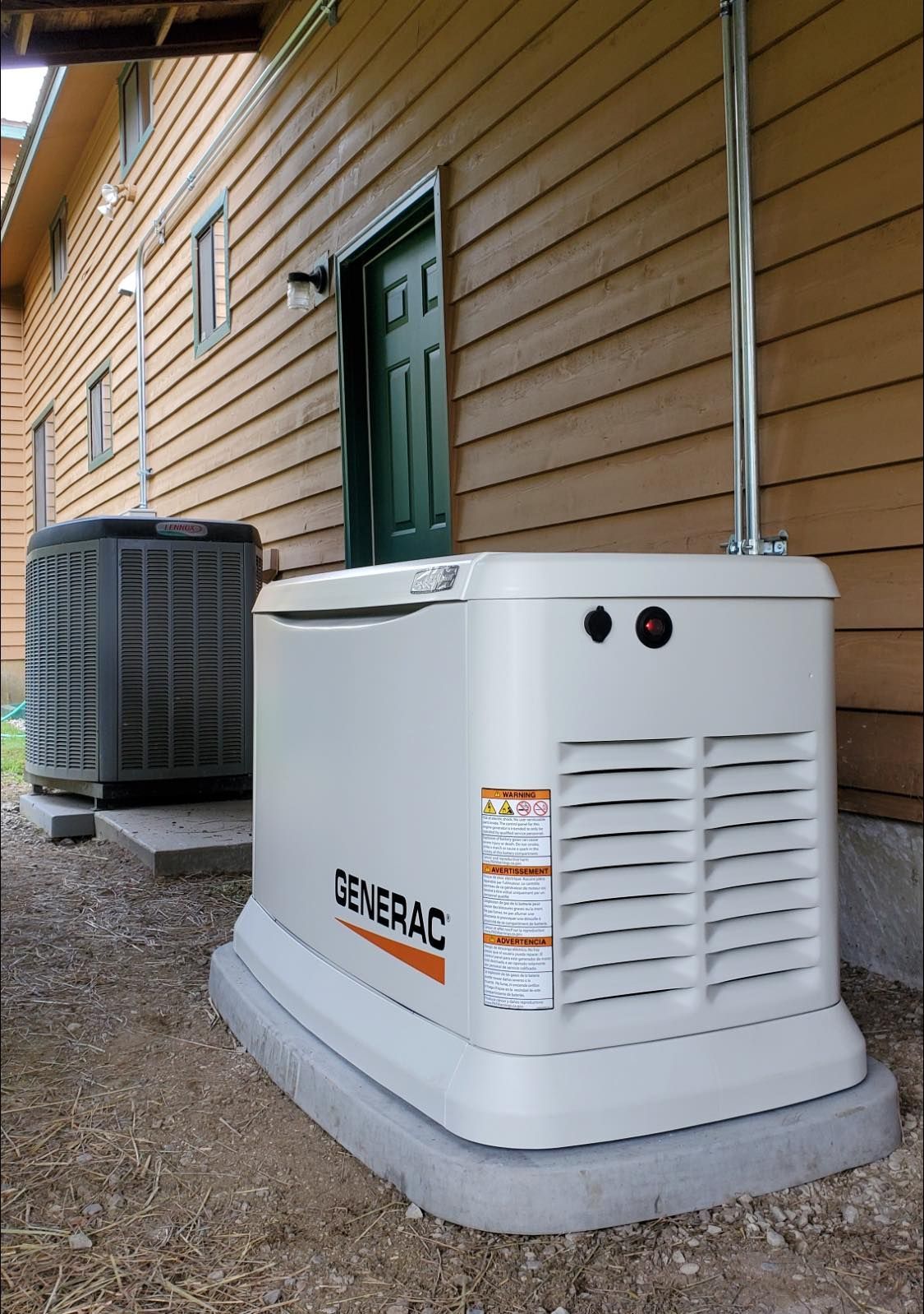 Portable Generac generator beside a house, with an air conditioner unit and green door in the background