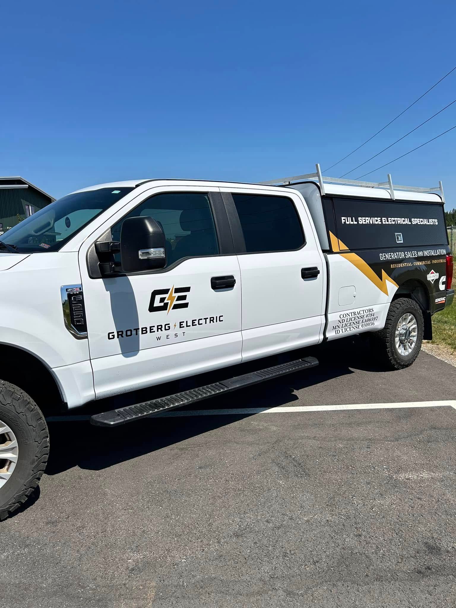 White utility pickup truck with company branding parked on a sunny street under a blue sky