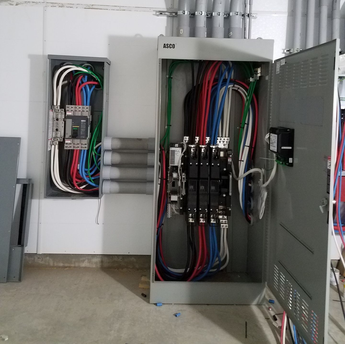 Electrical control panels with exposed multicolored wiring in an industrial room
