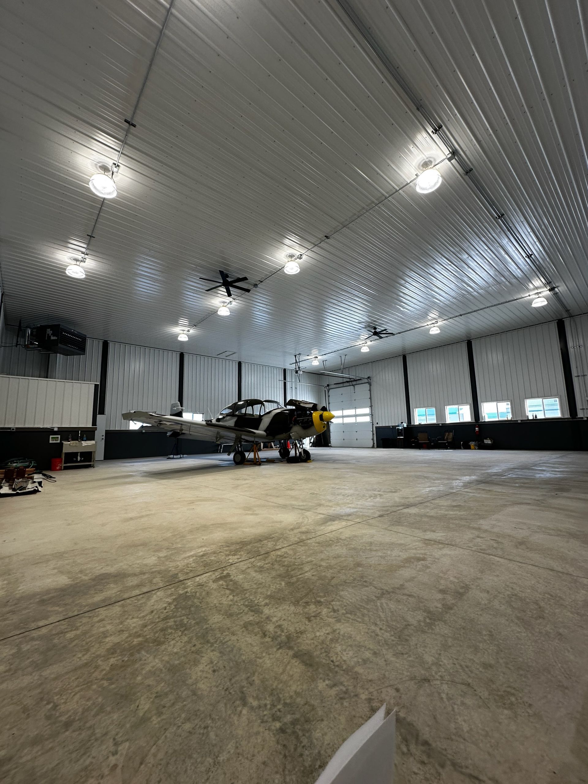 Large empty warehouse with a black pickup truck under bright ceiling lights and a curved white ceiling