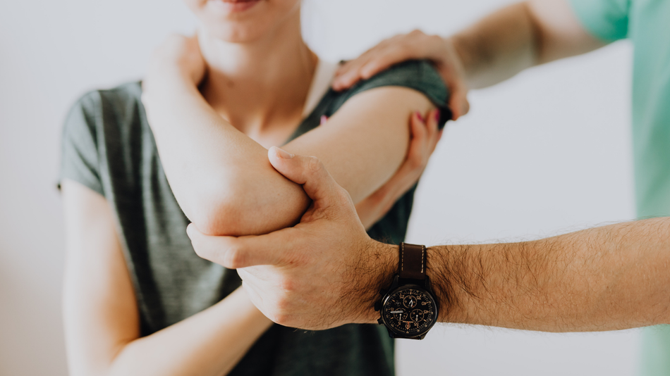 Person having their elbow examined by another person.
