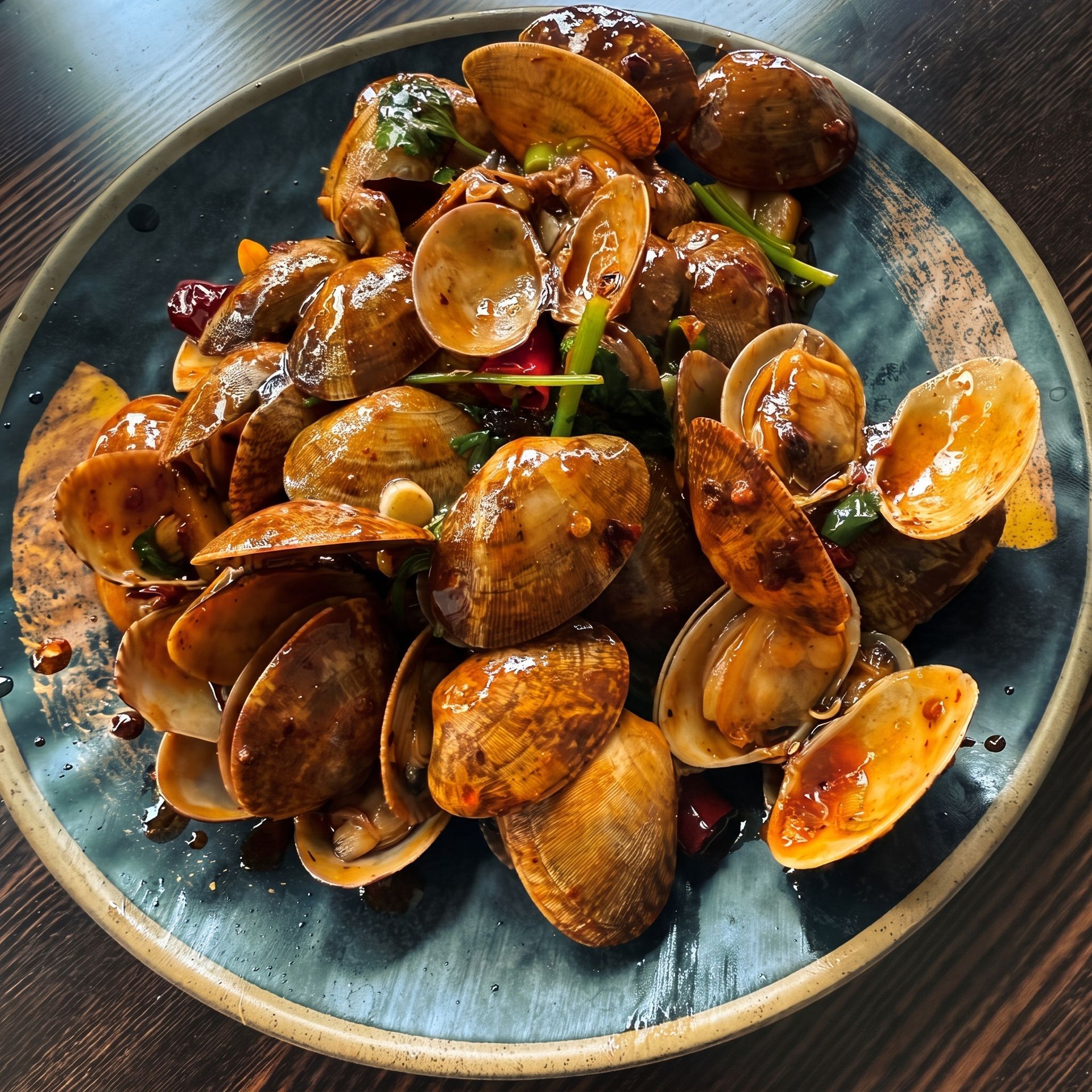 Seasoned clams in shells on a blue plate, garnished with herbs and sauce