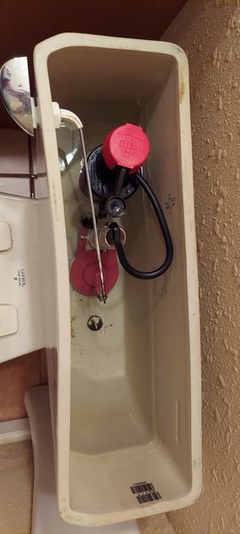 Bathroom sink with exposed plumbing, a red valve, and a towel on the side.