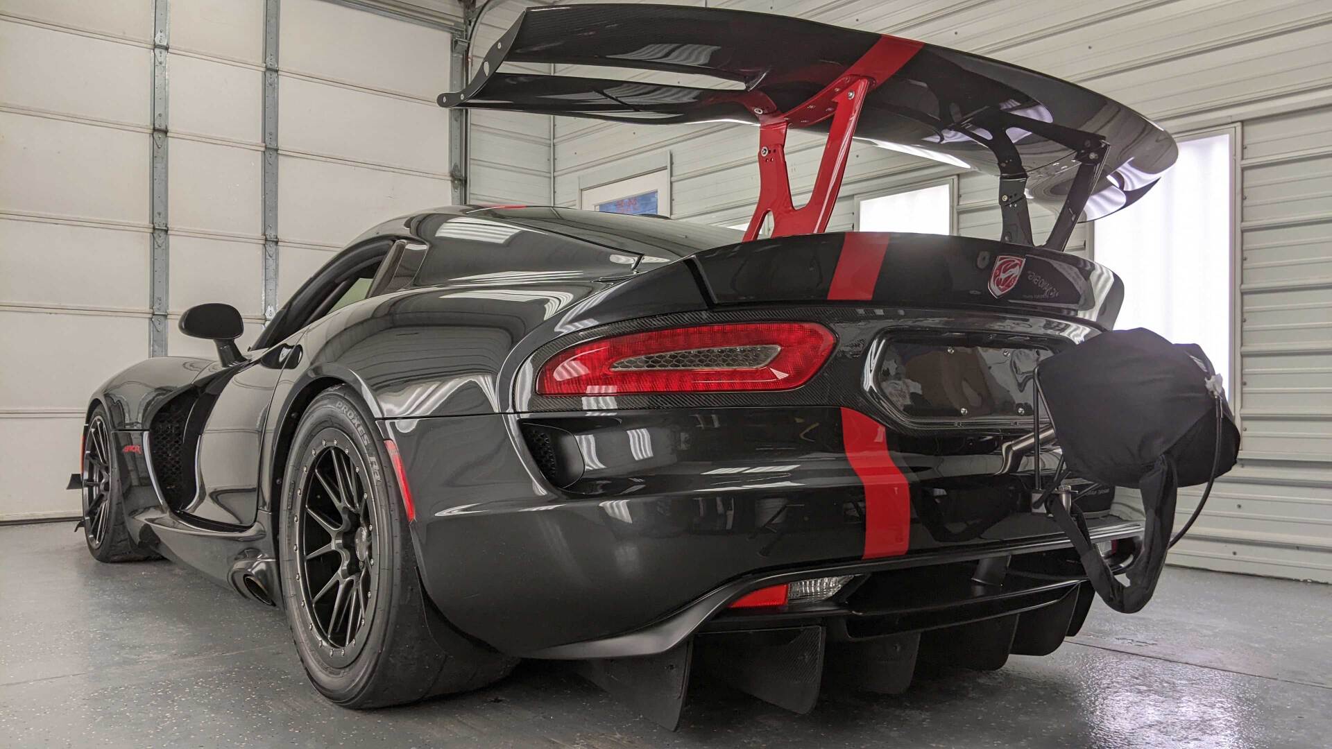 A black and red sports car is parked in a garage.