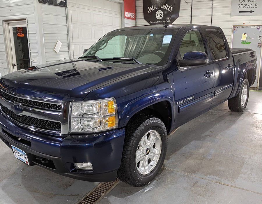 A blue chevrolet silverado pickup truck is parked in a garage.