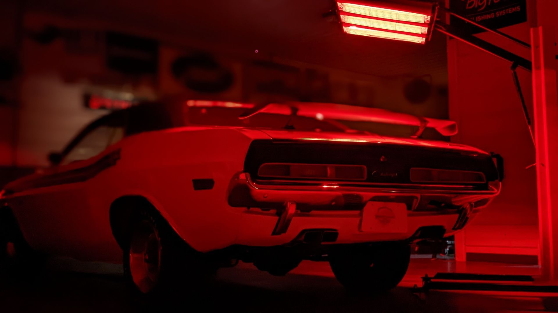 Muscle car under a red light in a garage.