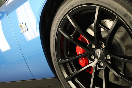 Blue car with black wheel and red brake caliper.
