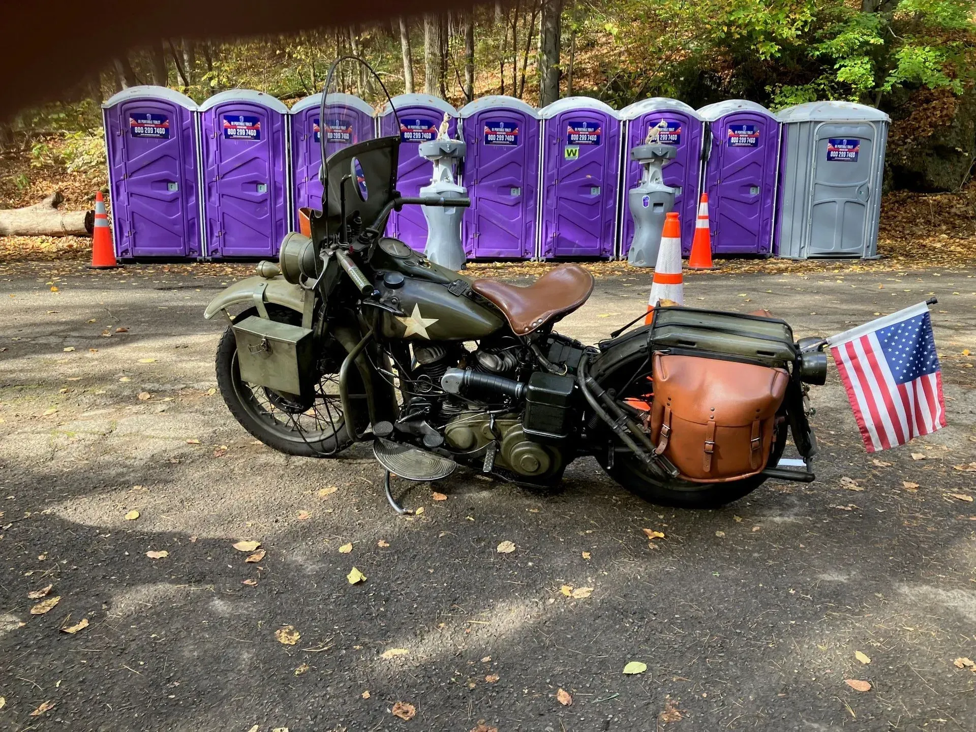 a motorcycle is parked in front of a row of portable toilets .