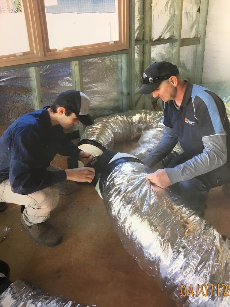 Two Workers Installing Ductwork in a Building — Craig Stewart Electrical in East Wagga Wagga, NSW