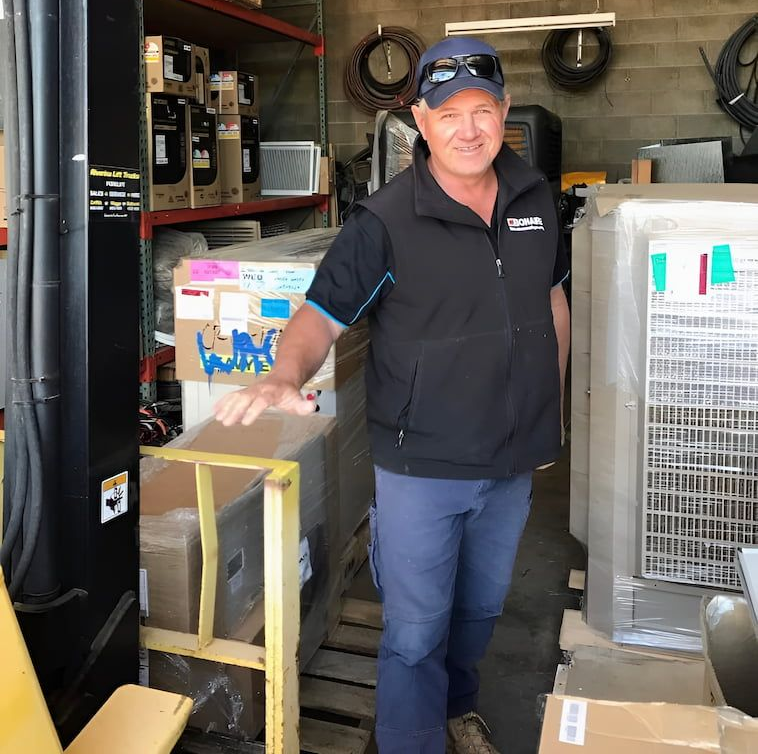 Man in Work Clothes Inside a Cluttered Storage Area — Craig Stewart Electrical in East Wagga Wagga, NSW